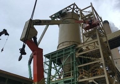 A crane is lifting a cement bag into the air.